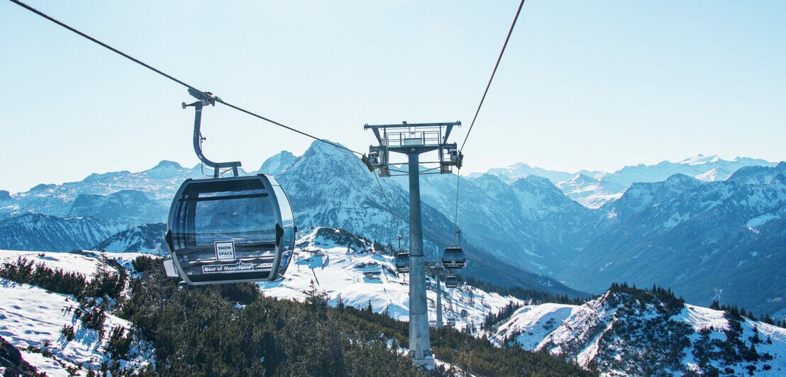 Skilift mit gläserner Gondel vor winterlichem Bergpanorama