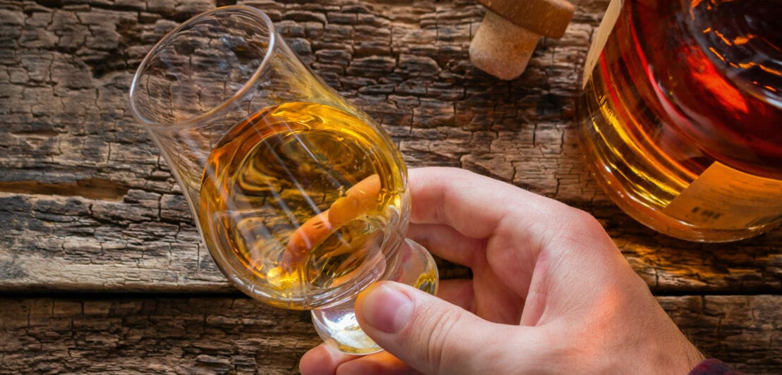 Eine Hand schwenkt Whisky in einem Nosing-Glas