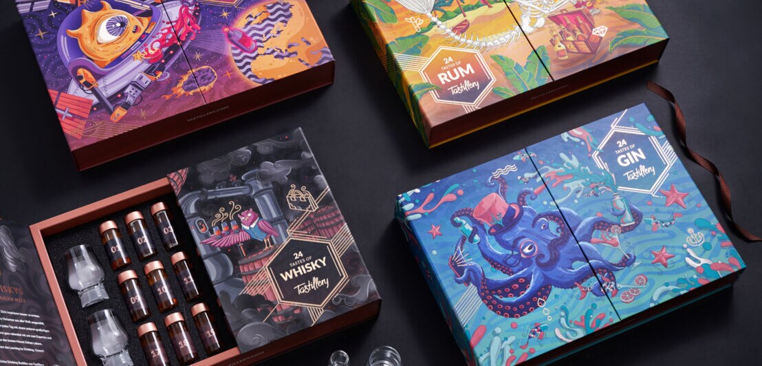 Vier künstlerisch gestaltete Adventskalender, eine geöffnete Box enthält kleine Gläser und Whisky-Shots