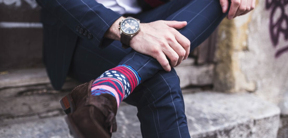 Ein Mann trägt bunt gemusterte Socken zu einem karierten Anzug.