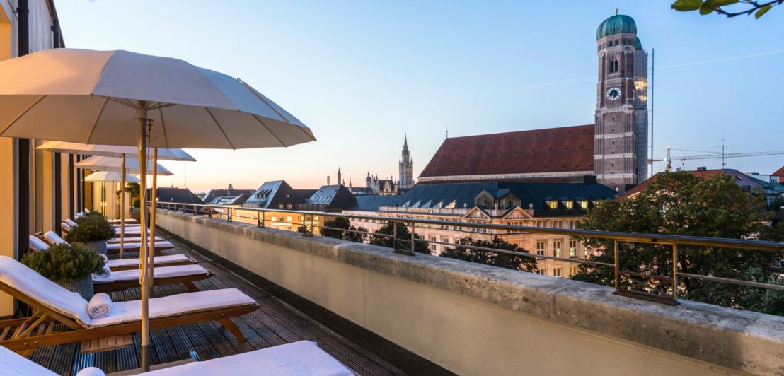 Sonnenterrasse mit Liegen und Schirmen und mit Blick auf Münchens Altstadt