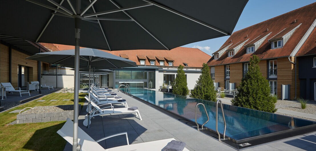 Sonnenterrasse mit Liegestühlen und modernem Außenpool aus Edelstahl in einer Hotelanlage