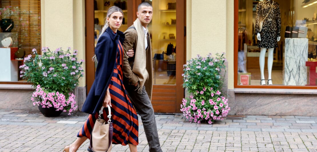Ein junges Paar geht Arm in Arm durch eine Einkaufsstraße