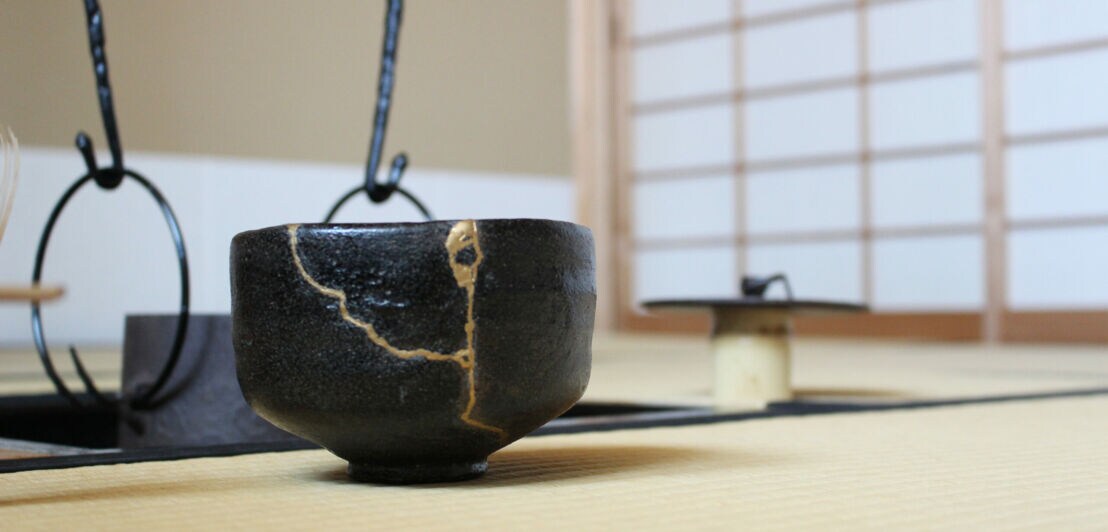 Eine mit Gold reparierte schwarze Teeschale in einem japanischen Tee-Zeremonie-Raum
