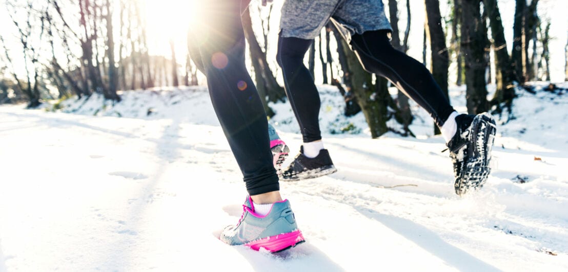 Die Beine von zwei Läufer:innen im Schnee
