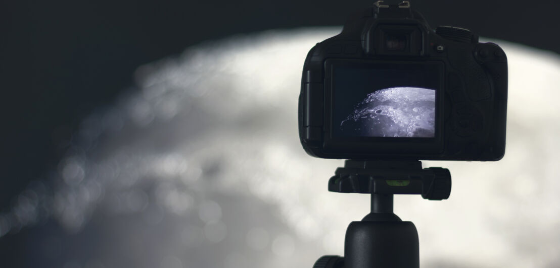 Auf einem Stativ befestigte Kamera mit Bild des Mondes auf dem Display