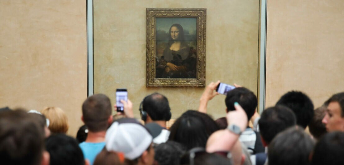 Gemälde der Mona Lisa an der Wand im Museum mit Smartphones und Köpfen von Betrachtern im Vordergrund