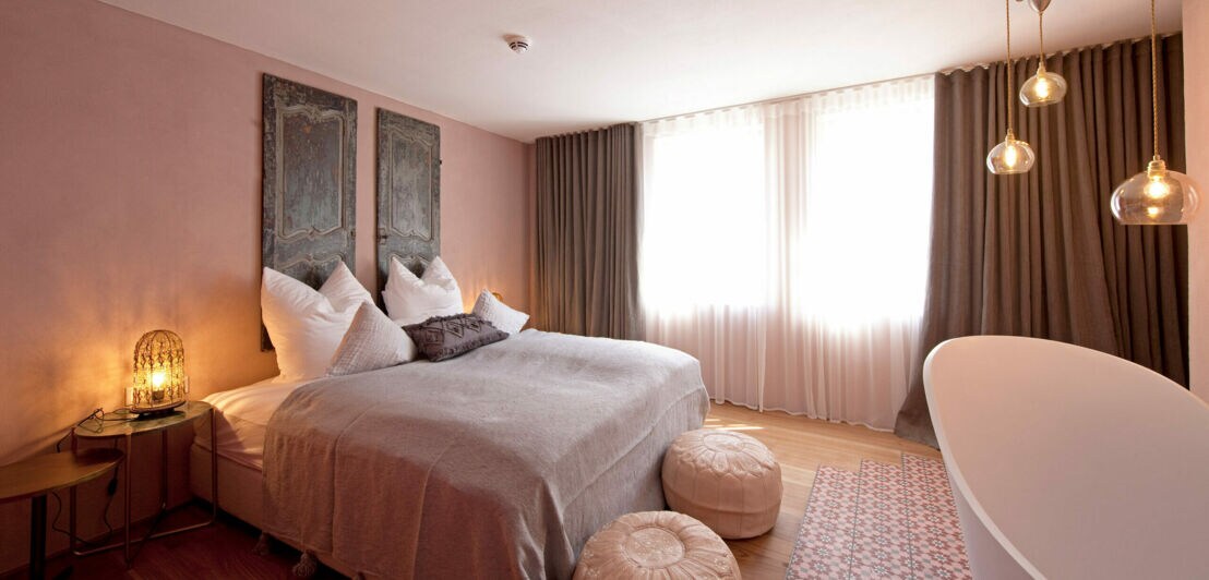 Hotelzimmer in Pastellfarben mit Doppelbett und Badewanne