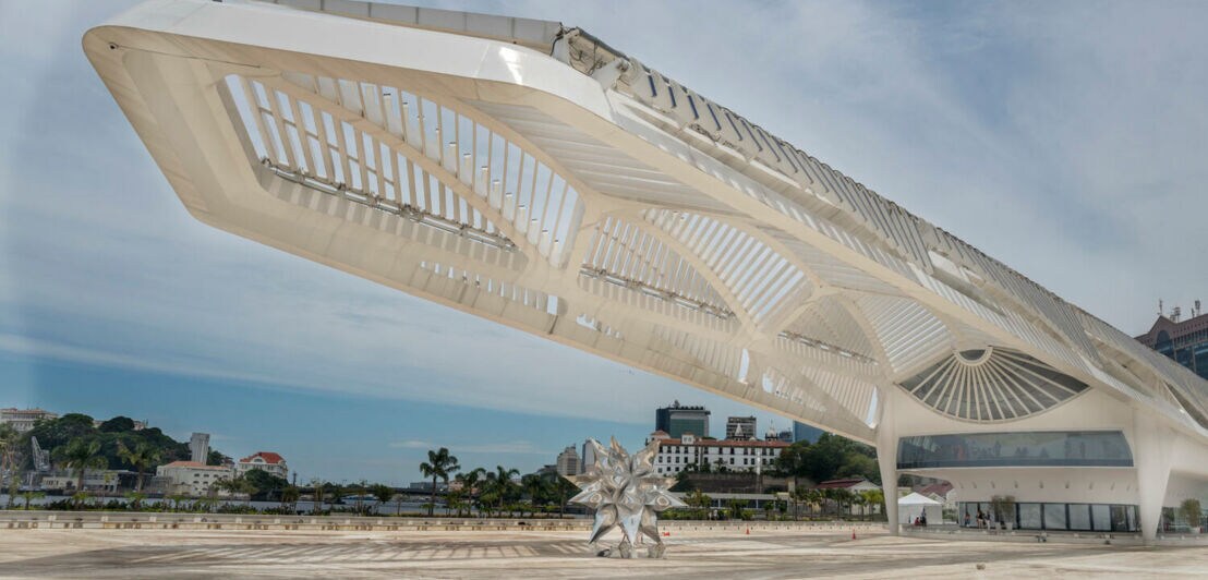 Weißes, futuristisches Gebäude eines Museums mit ausladender Architektur auf einem Vorplatz