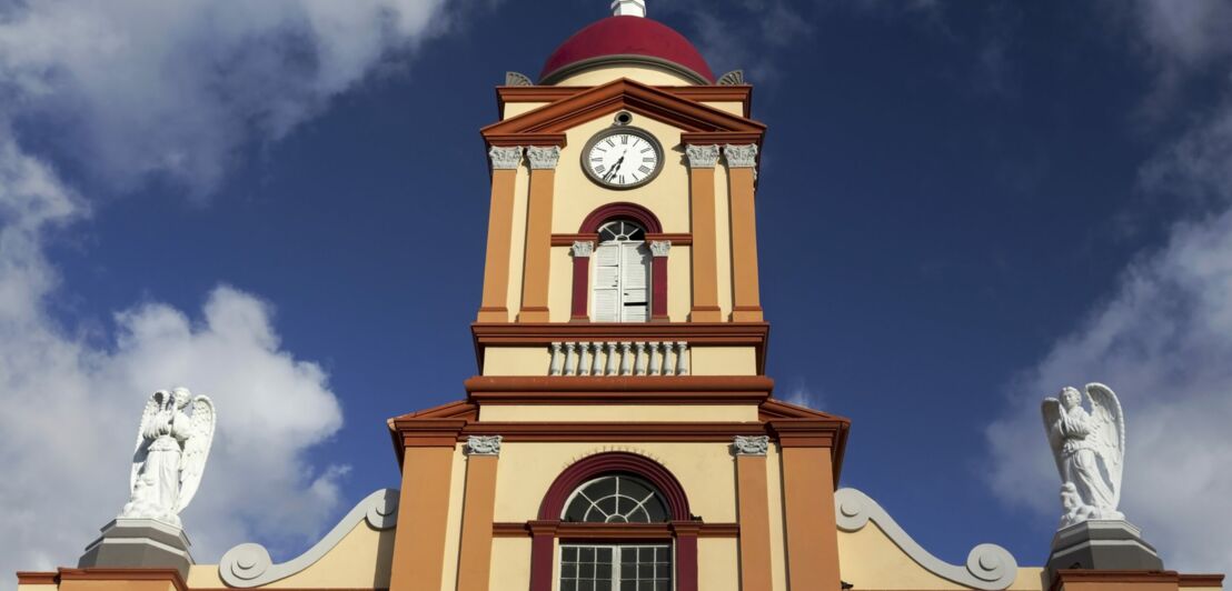 Eine Kirchturm mit Uhr, im Hintergrund blauer Himmel