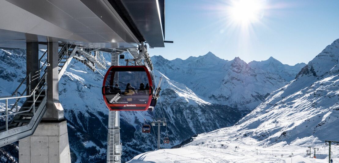 Blick über ein Skigebiet mit einer Seilbahn und Bergen im Hintergrund.