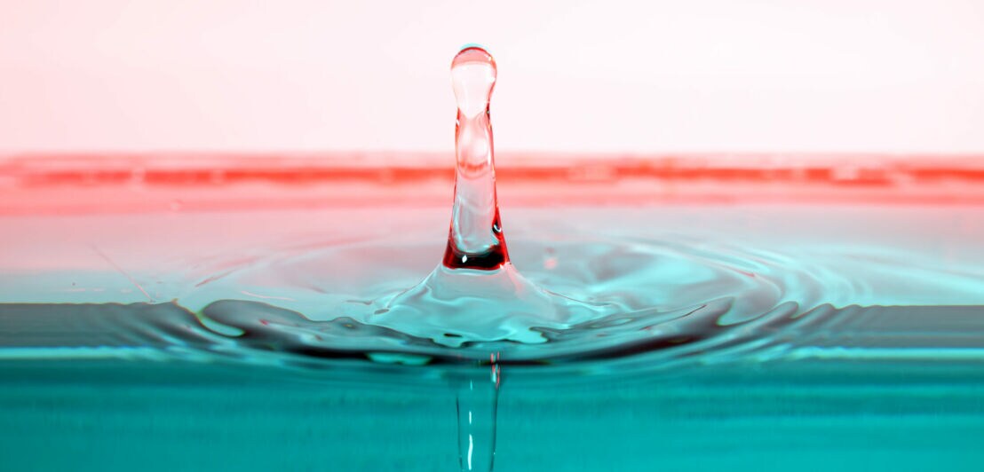 Ein Wassertropfen spiegelt sich in der Wasseroberfläche.