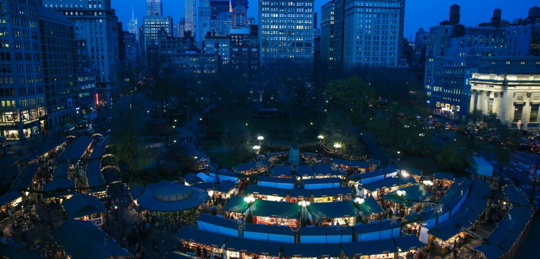 Blick aus der Höhe auf den Union Square mit beleuchteten Marktständen bei Dunkelheit