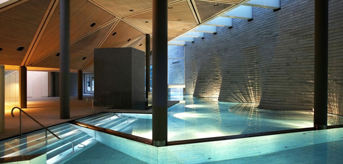 Überdachter, beleuchteter Pool in moderner Architektur mit Granit-Wänden