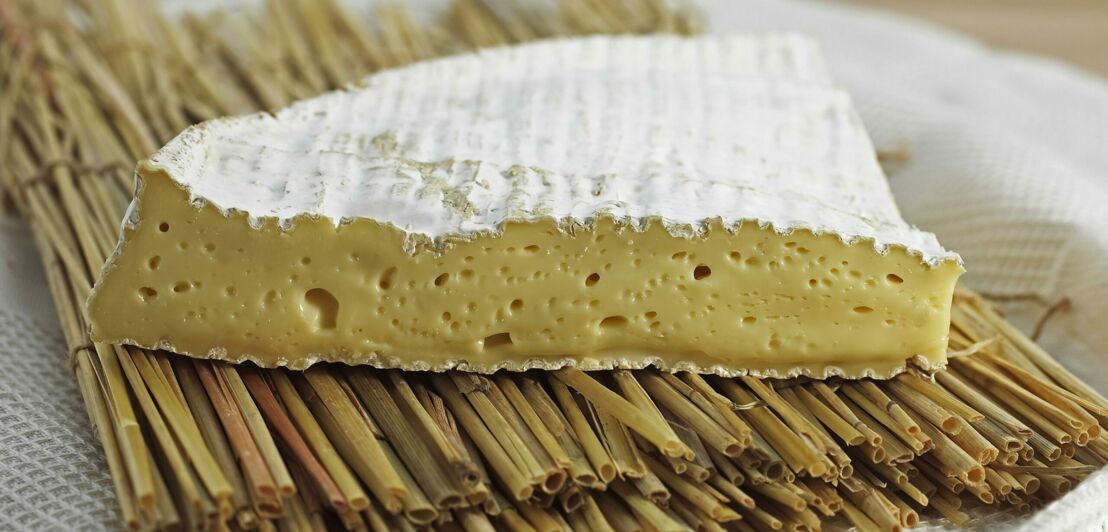 Ein Stück Brie-Käse auf einer Bambusmatte angerichtet
