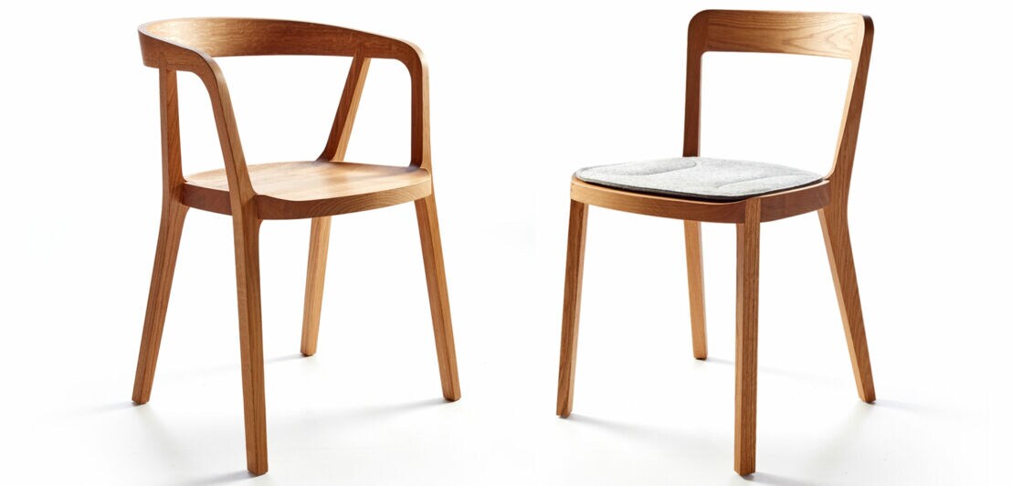 Zwei ergonomisch geformte Esstischstühle aus hellem Massivholz