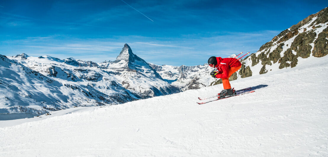 Skifahrer:in fährt die Piste runter, im Hintergrund das Matterhorn