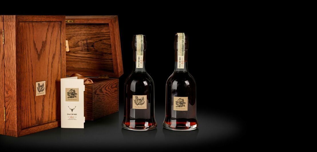 Zwei Flaschen des Whiskys Dalmore 62 Jahre neben ihren Verpackungen aus Holz
