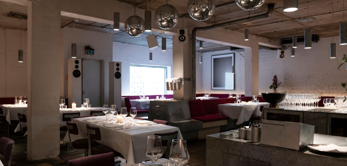 Innenraumaufnahme eines modernen Restaurants im Industrial-Stil mit elegant gedeckten Tischen
