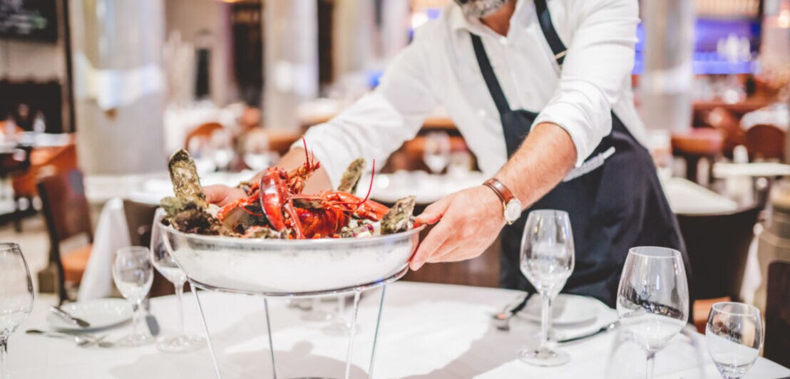 Kellner serviert eine große Schale mit Austern und Meeresfrüchten