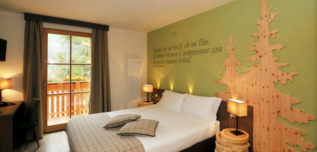 Ein Hotelzimmer mit Doppelbett, Dekorationselementen aus Holz und einem Balkon mit Blick ins Grüne