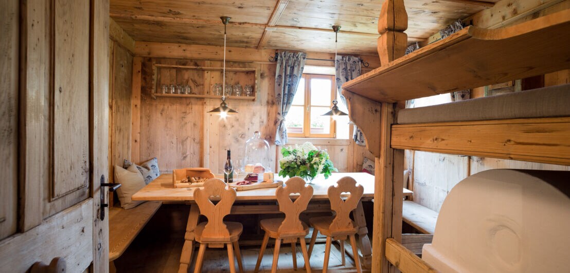 Eine gemütliche Holzstube mit Esstisch und Ofenbank