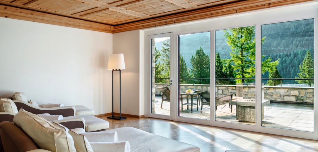 Elegant eingerichtetes Zimmer mit Aussicht auf die Terrasse und den Wald
