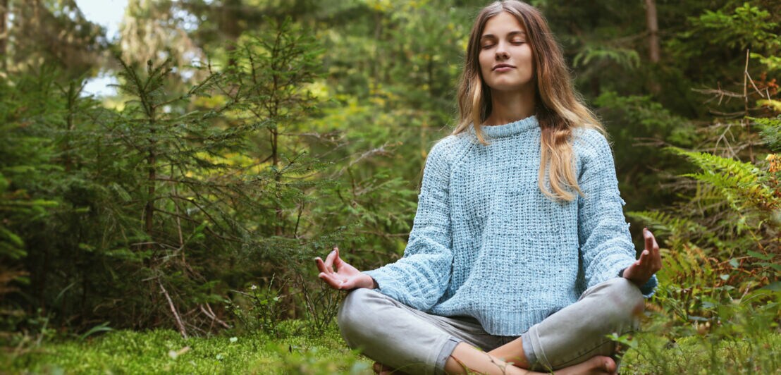 Frau meditiert im Wald
