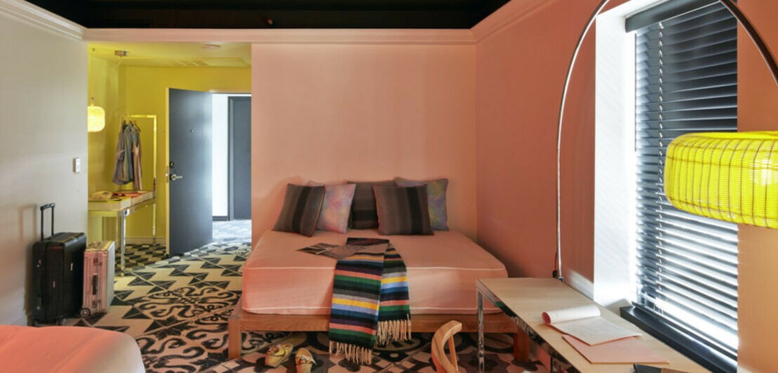 Modernes, geradliniges Hotelzimmer mit farbigen Wänden und Accessoires sowie einem gemusterten Teppichboden
