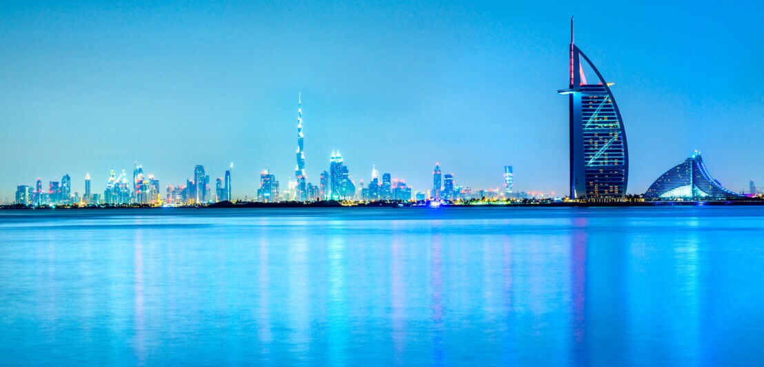 Skyline von Dubai mit Wasser im Vordergrund am Abend