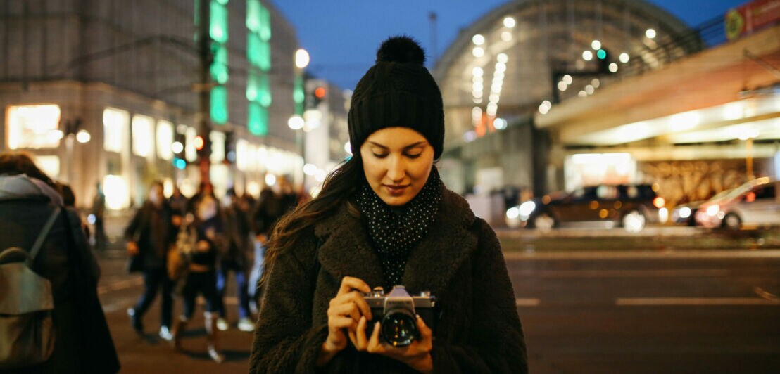 Eine Frau hält eine Kamera in der Hand und schaut auf das Display