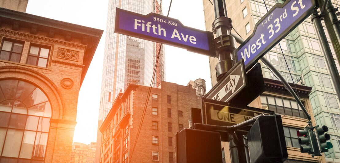 Straßenschild an einer Kreuzung der Fifth Avenue in Manhattan mit Gebäuden im Hintergrund