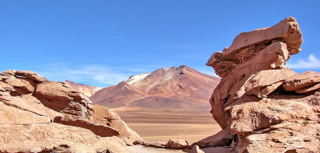 Einige Gesteinsformationen in einer Wüste mit Berg im Hintergrund