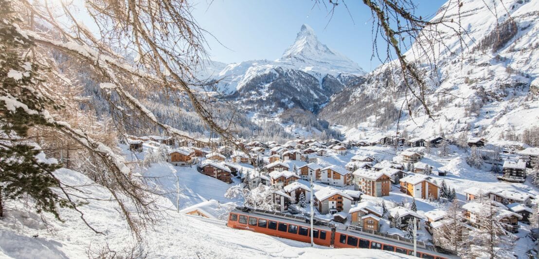 Ein schneebedecktes Dorf, im Hintergrund das Matterhorn