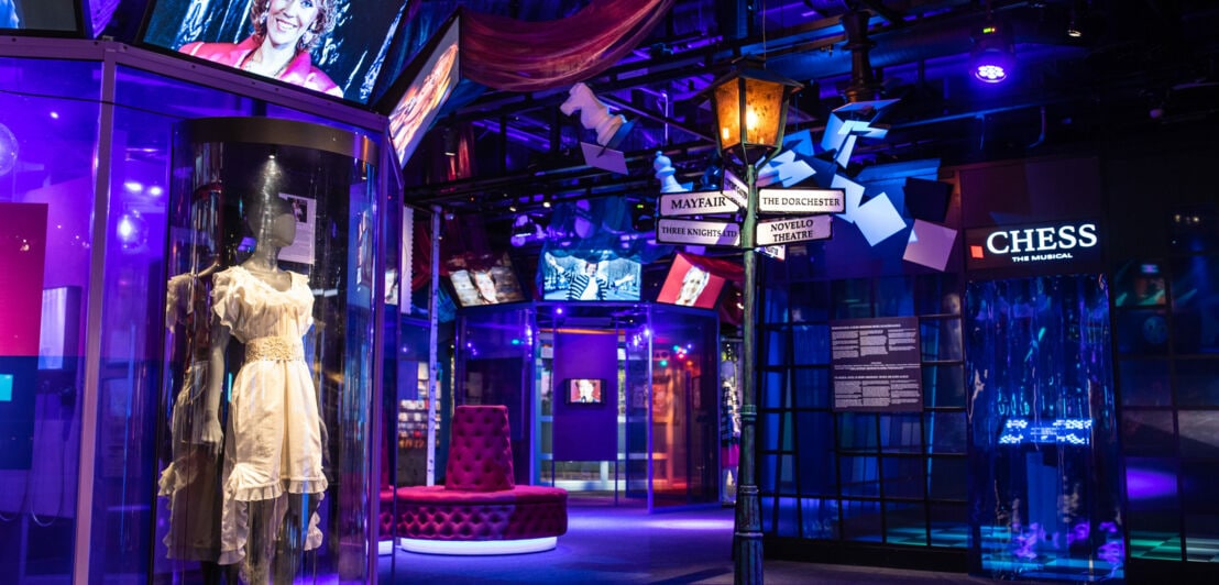 Innenansicht des ABBA-Museums mit Exponaten, gemütlichen Sitzgelegenheiten und einer blau-violetten Beleuchtung