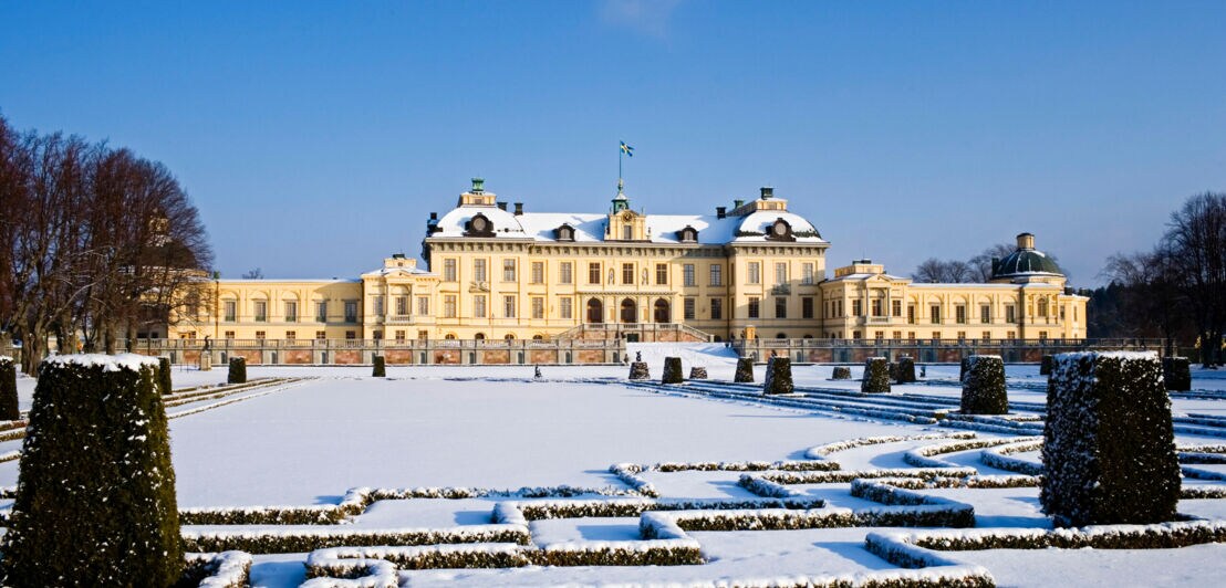 Das eingeschneite Schloss Drottningholm mit seinem Schlossgarten bei Sonnenschein