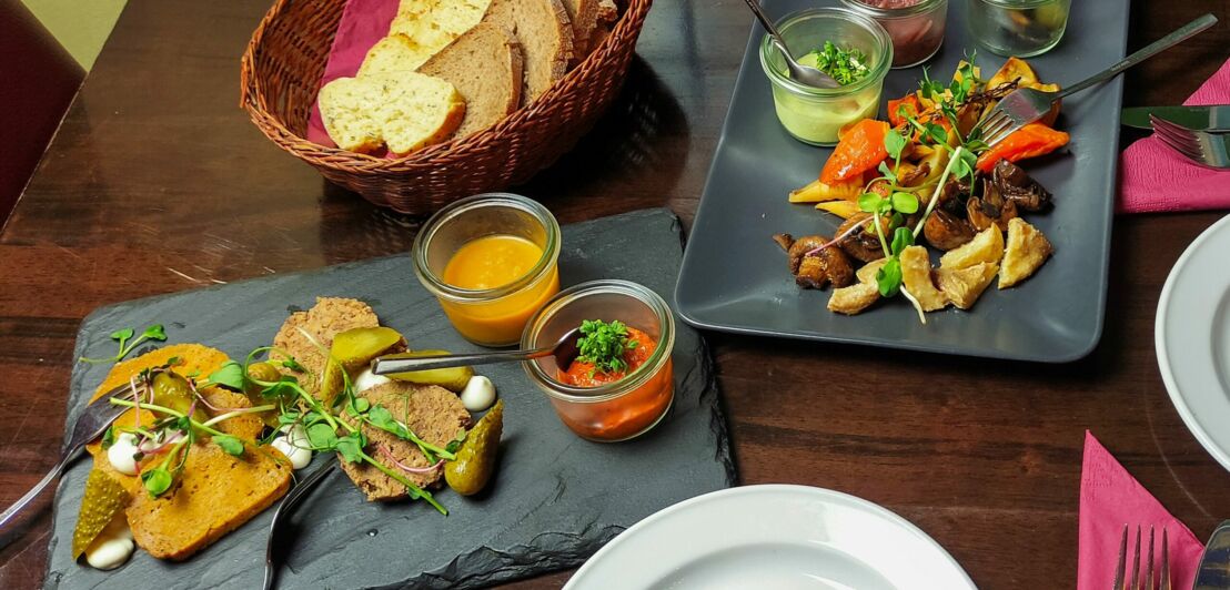 Verschiedene vegetarische Tapas mit Dips und einem Brotkorb auf einem gedeckten Restauranttisch