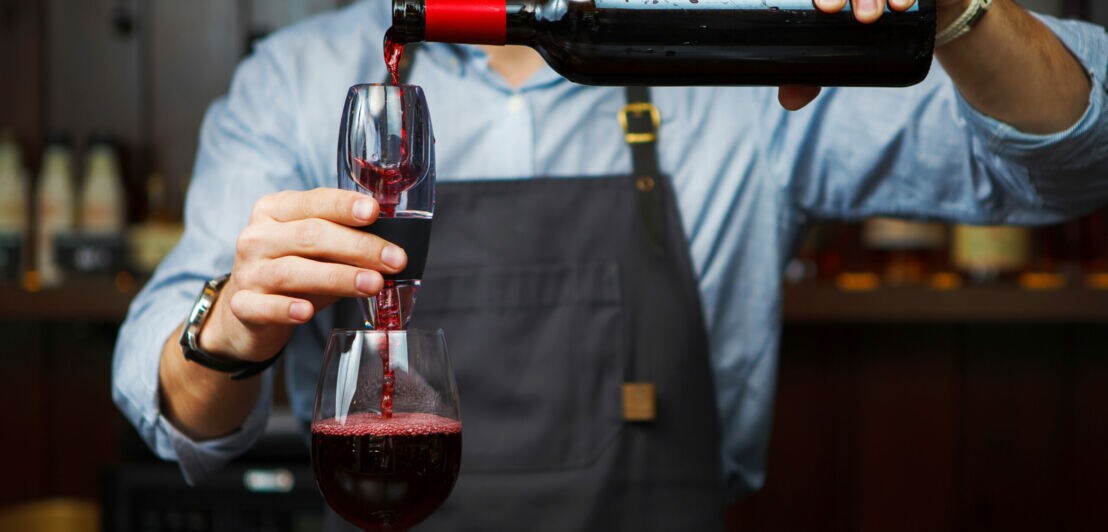 Männlicher Sommelier gießt Rotwein durch Belüfter ins Glas