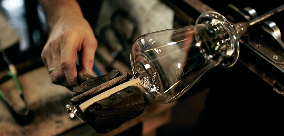 In einer Glasmanufaktur wird der Stil eines Weinglases geformt.