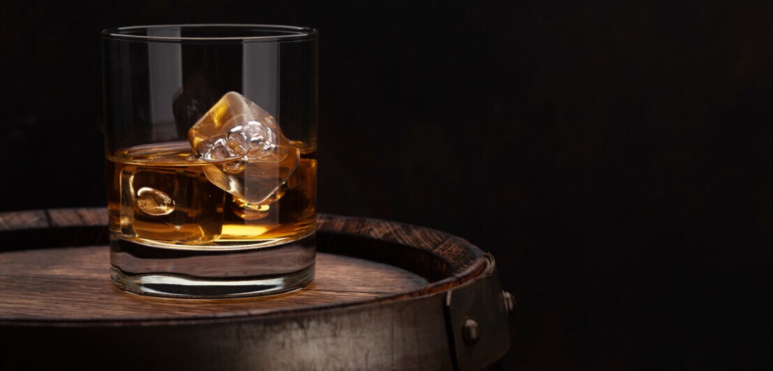 Ein Glas Whisky steht auf einem Holzfass