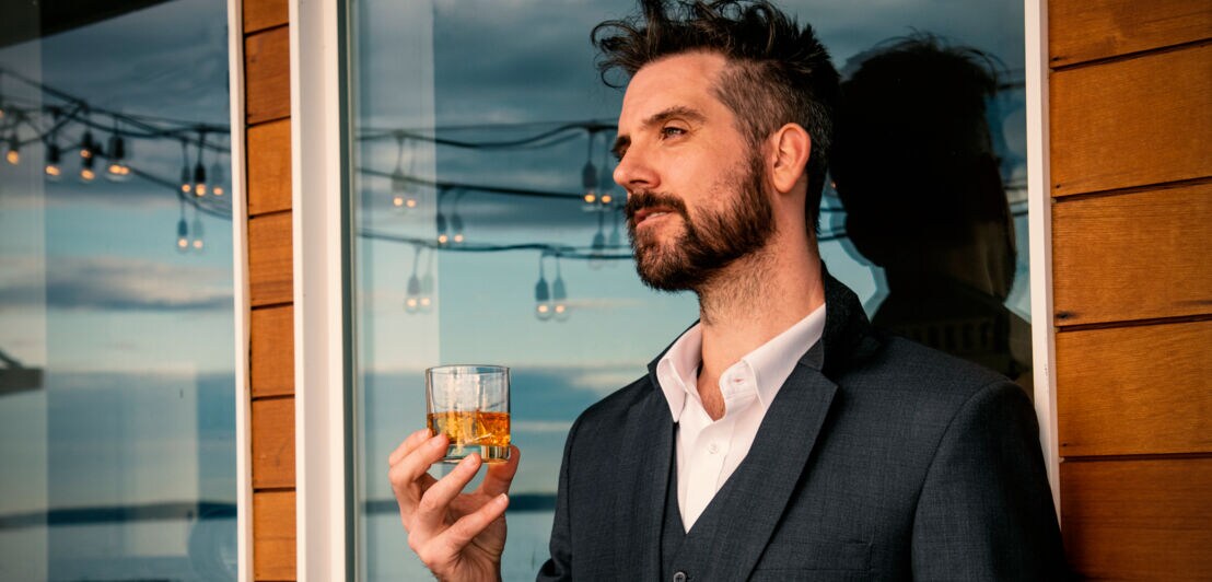 Ein Mann trinkt einen Whisky am Abend