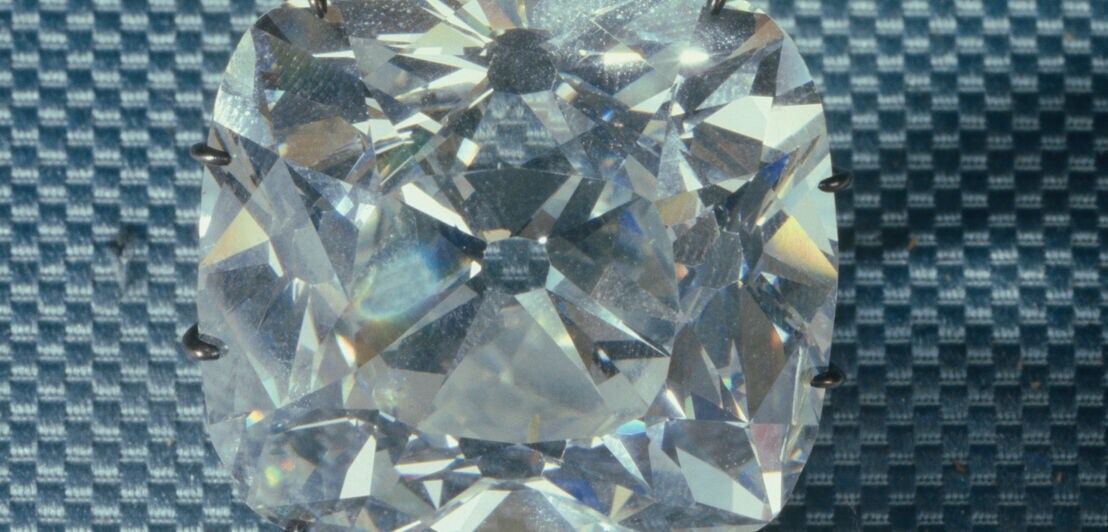 Ein eingefasster farbloser Diamant auf grauem Untergrund