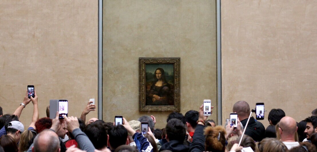 Zahlreiche Besucher fotografieren dicht gedrängelt das Gemälde der Mona Lisa im Museum mit ihren Smartphones