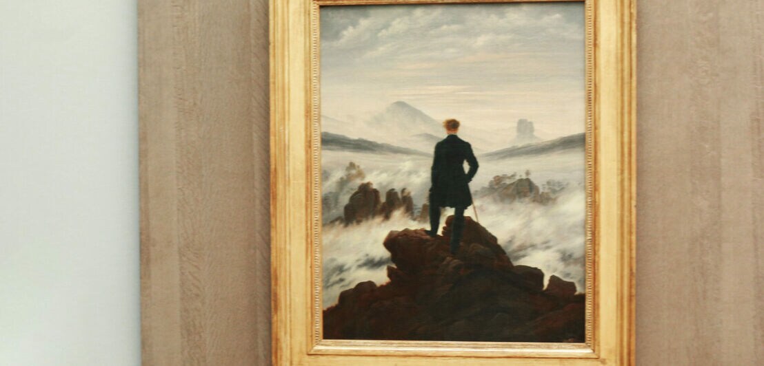 Das Gemälde Der Wanderer über dem Nebelmeer in einem goldenen Rahmen an der Wand