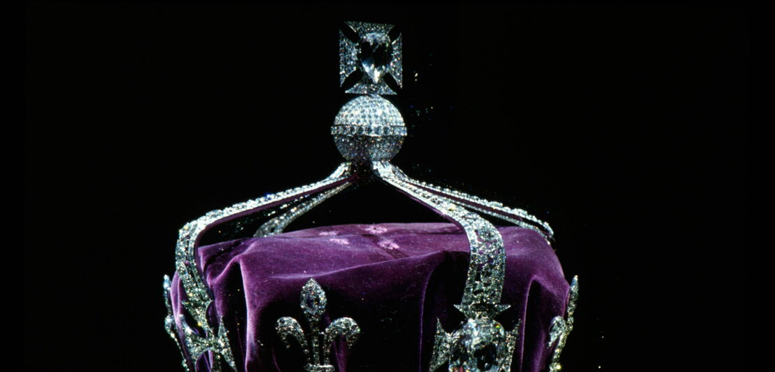 Eine mit Diamanten besetzte, aus Platin gefertigte Krone mit lilafarbenem Samt vor schwarzem Hintergrund