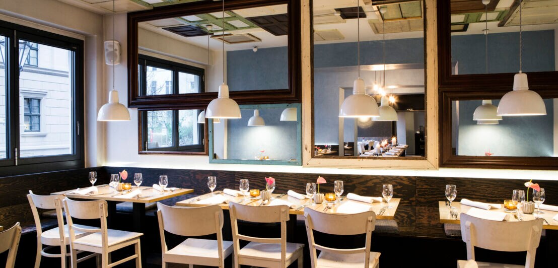 Interieur eines modernen, schicken Restaurants mit gedeckten Tischen und Spiegelwand
