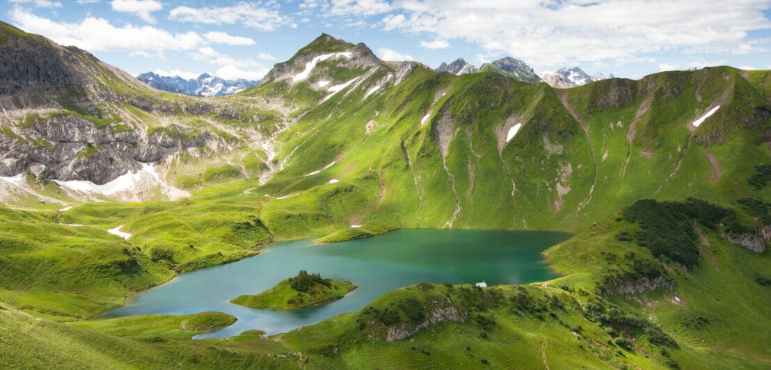 Ein Bergsee mit einer Insel zwischen grünen Bergkämmen