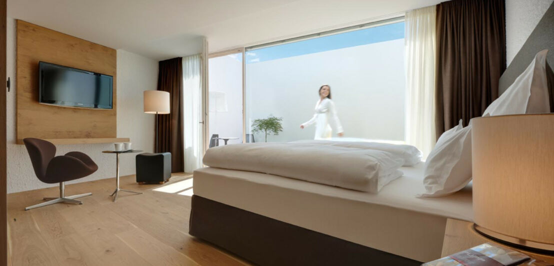 Ein Hotelbett steht vor einem großformatigen Fenster