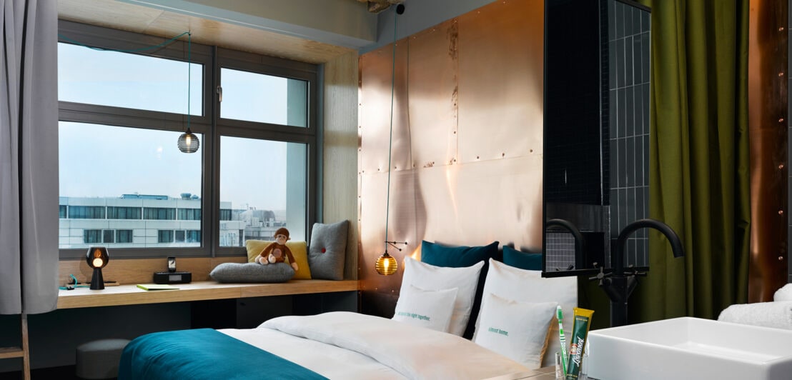 Innenansicht eines Hotelzimmers mit Kupferelementen, Doppelbett und Blick über Berlin