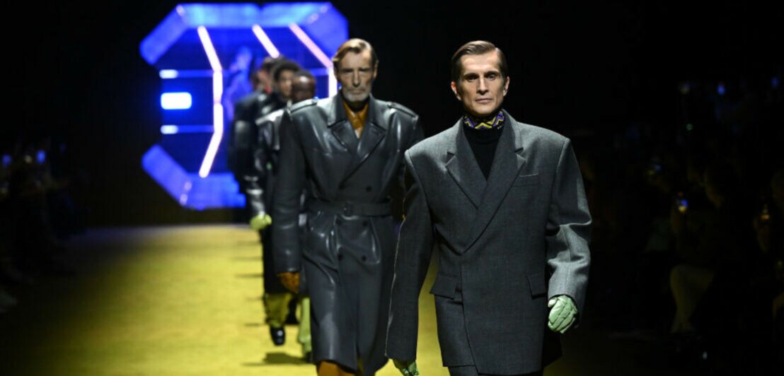 Mehrere Models laufen über den Laufsteg und präsentieren Männermode von Prada